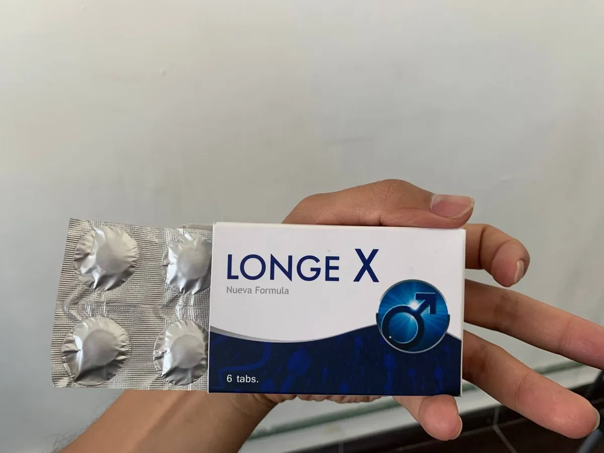 Mano sosteniendo la caja de Longe X Nueva Fórmula con el blíster de tabletas asomando